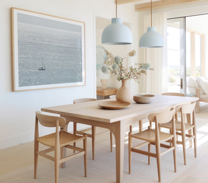 Large minimalist ocean print showing a smooth seascape with gentle ocean waves meeting a clear horizon line, one single sail boat in the distance. This calm nautical print provides a serene view in Dana Point, San Diego, California. Photograph in minimalist mock up.