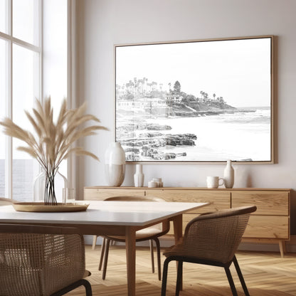 Fine art of WindanSea Beach, La Jolla California horizontal landscape black and white print by Southern California photographer Kim Dybczak of Salt Creek Prints, featuring a powerful waves crashing against the rocky shore of California coast. Beach homes and palm trees sit atop the cliffside, with stairs leading down to a sheltered area. Photograph in minimalist framed dining room mock up