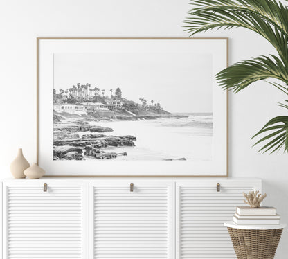 Fine art of WindanSea Beach, La Jolla California horizontal landscape black and white print by Southern California photographer Kim Dybczak of Salt Creek Prints, featuring a powerful waves crashing against the rocky shore of California coast. Beach homes and palm trees sit atop the cliffside, with stairs leading down to a sheltered area. Photograph in minimalist framed mock up