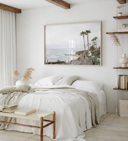 Horizontal coastal photography featuring a scenic view of the ocean with palm trees in the background, set against a white sky, located in Laguna California. Photograph in minimalist mock up.