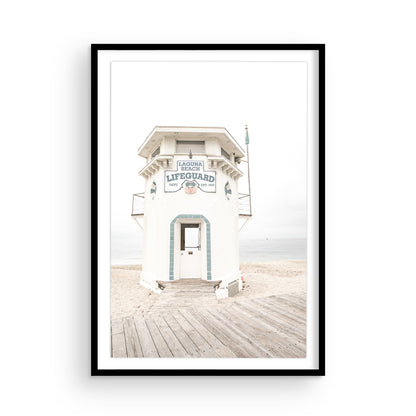 Vertical coastal photography of a white lifeguard tower at Laguna Beach, California, with a clear blue sky and ocean in the background. This neutral ocean print highlights coastal architecture. Photograph in minimalist mock up.