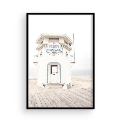 Vertical coastal photography of a white lifeguard tower at Laguna Beach, California, with a clear blue sky and ocean in the background. This neutral ocean print highlights coastal architecture. Photograph in minimalist mock up.