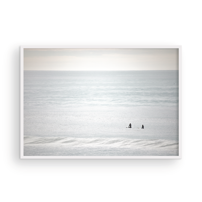 Horizontal minimalist ocean art with a close-up blue waves print of water, featuring subtle ripples and soft textures, ideal as a neutral ocean print, two surfers sit and watch the waves. Photograph in minimalist mock up.
