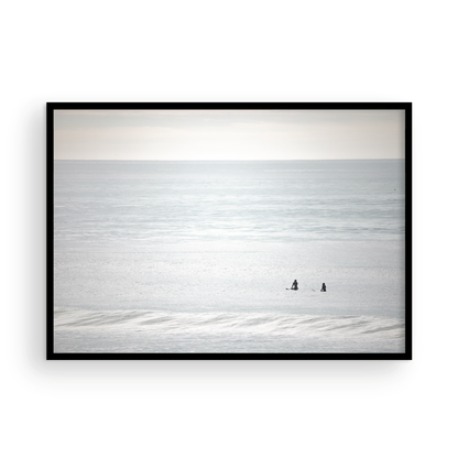 Horizontal minimalist ocean art with a close-up blue waves print of water, featuring subtle ripples and soft textures, ideal as a neutral ocean print, two surfers sit and watch the waves. Photograph in minimalist mock up.