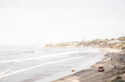 Landscape surf wall decor at Pacific Beach, San Diego, with numerous surfers in the water and a residential cliffside. 