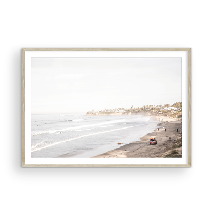 Landscape surf wall decor at Pacific Beach, San Diego, with numerous surfers in the water and a residential cliffside. Photograph in minimalist mock up.