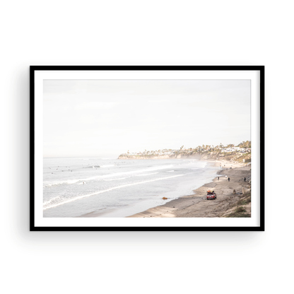 Landscape surf wall decor at Pacific Beach, San Diego, with numerous surfers in the water and a residential cliffside. Photograph in minimalist mock up.