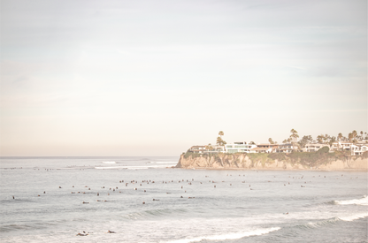 Landscape San Diego beach print of Tourmaline Beach, Pacific Beach, San Diego, showing a large group of surfers in the water near a residential cliff. This surf vibes print captures the local surf scene. 