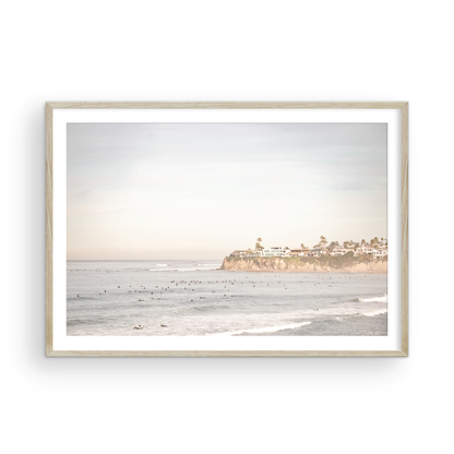 Landscape San Diego beach print of Tourmaline Beach, Pacific Beach, San Diego, showing a large group of surfers in the water near a residential cliff. This surf vibes print captures the local surf scene. Photograph in minimalist mock up.