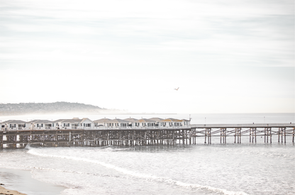 Landscape coastal photography of Crystal Pier in Pacific Beach, San Diego, extending into the calm ocean with gentle waves.