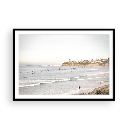Landscape surf wall decor at Tourmaline Surf Park, Pacific Beach, San Diego, with numerous surfers in the water and a residential cliffside. Photograph in minimalist mock up.