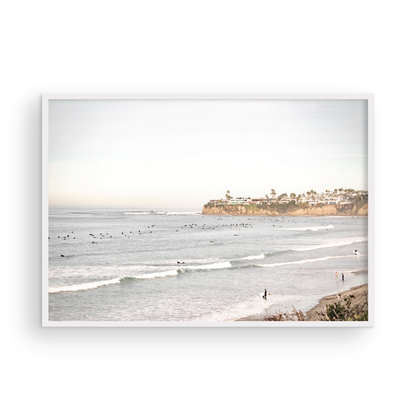 Landscape surf wall decor at Tourmaline Surf Park, Pacific Beach, San Diego, with numerous surfers in the water and a residential cliffside. Photograph in minimalist mock up.