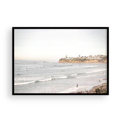 Landscape surf wall decor at Tourmaline Surf Park, Pacific Beach, San Diego, with numerous surfers in the water and a residential cliffside. Photograph in minimalist mock up.