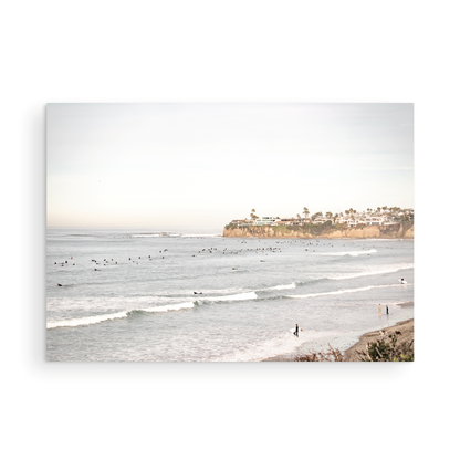 Landscape surf wall decor at Tourmaline Surf Park, Pacific Beach, San Diego, with numerous surfers in the water and a residential cliffside. Photograph in minimalist mock up.