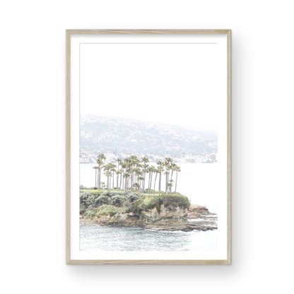 Vertical coastal photography of Laguna Beach, San Diego, featuring a fine art giclee print featuring palm trees on a small island in a body of water. Photograph in minimalist mock up.