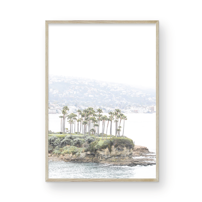Vertical coastal photography of Laguna Beach, San Diego, featuring a fine art giclee print featuring palm trees on a small island in a body of water. Photograph in minimalist mock up.