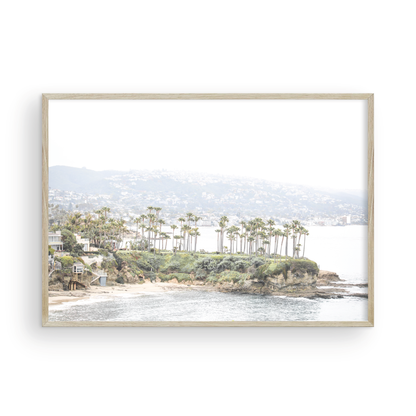 Horizontal coastal photography of Laguna Beach, San Diego, featuring a fine art giclee print featuring palm trees on a small island in a body of water. Photograph in minimalist mock up.