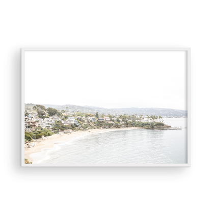Horizontal coastal photography featuring a beach scene with a calm ocean and beach homes lining the shoreline, located in Laguna California. Photograph in minimalist mock up.