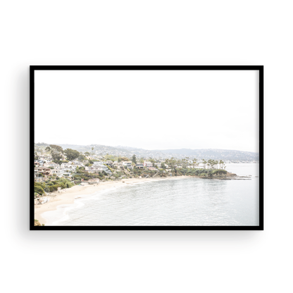Horizontal coastal photography featuring a beach scene with a calm ocean and beach homes lining the shoreline, located in Laguna California. Photograph in minimalist mock up.