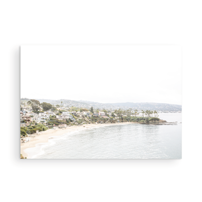 Horizontal coastal photography featuring a beach scene with a calm ocean and beach homes lining the shoreline, located in Laguna California. Photograph in minimalist mock up.