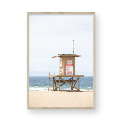 A wide landscape coastal photography view of Newport Beach in Southern California, featuring a lifeguard tower and walls on the beach. Photograph in minimalist mock up.