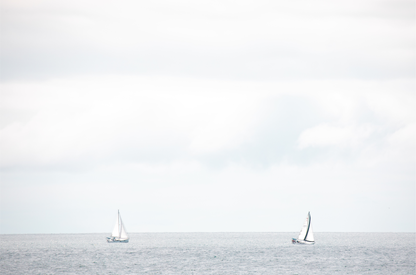 Minimalist ocean print featuring two sailboats on a calm ocean under a vast, bright sky. This serene seascape is ideal for coastal, nautical theme wall art. Photograph in minimalist mock up