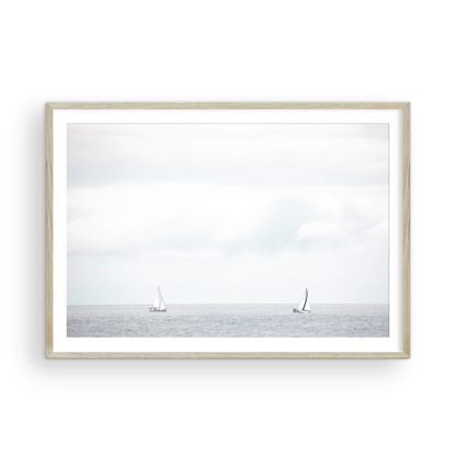 Minimalist ocean print featuring two sailboats on a calm ocean under a vast, bright sky. This serene seascape is ideal for coastal, nautical theme wall art. Photograph in minimalist mock up