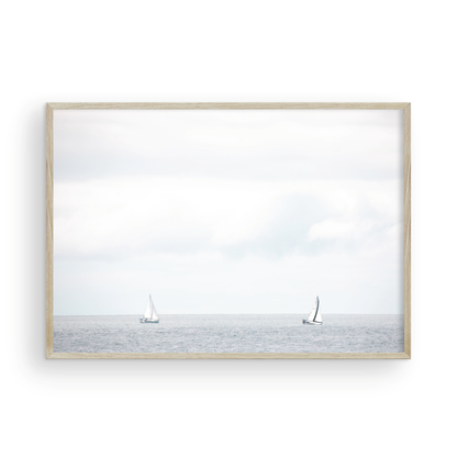 Minimalist ocean print featuring two sailboats on a calm ocean under a vast, bright sky. This serene seascape is ideal for coastal, nautical theme wall art. Photograph in minimalist mock up
