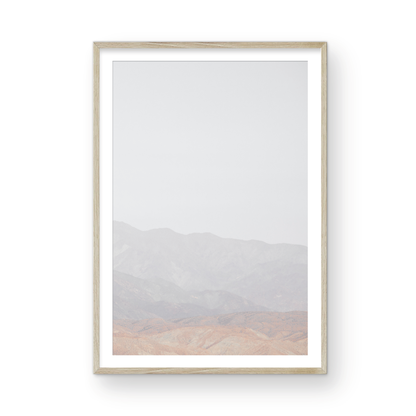 Minimalist art print of hazy mountains layered in soft tones, creating a calm ocean print aesthetic. This vertical minimalist art print can fit a neutral ocean print theme. Photograph in minimalist mock up.