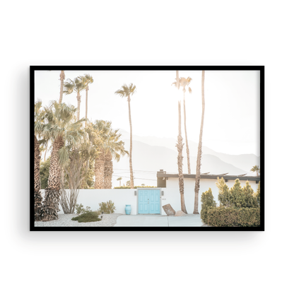 Coastal print of a Palm Springs home with a bright blue door, surrounded by tall palm trees and distant mountains, embodying summer vibes wall art. Photograph in minimalist mock up.