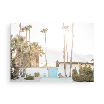 Coastal print of a Palm Springs home with a bright blue door, surrounded by tall palm trees and distant mountains, embodying summer vibes wall art. Photograph in minimalist mock up.