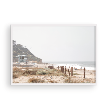 Landscape coastal photography of a light-colored lifeguard tower at a Southern California beach, with a rustic wooden fence leading towards the ocean waves. This tranquil beachscape print is ideal for beach cottage wall decor or a calm beach print. Photograph in minimalist mock up.