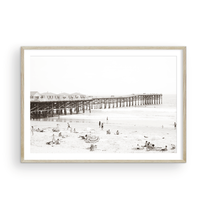 Sepia beach photo of Crystal Pier in Pacific Beach, San Diego, with people on the sandy beach. This framed coastal print showcases iconic beach scenes. Photograph in minimalist mock up.