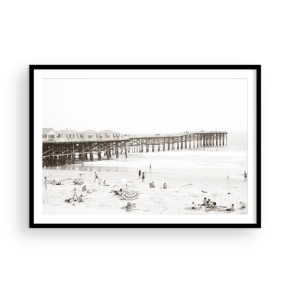 Sepia beach photo of Crystal Pier in Pacific Beach, San Diego, with people on the sandy beach. This framed coastal print showcases iconic beach scenes. Photograph in minimalist mock up.