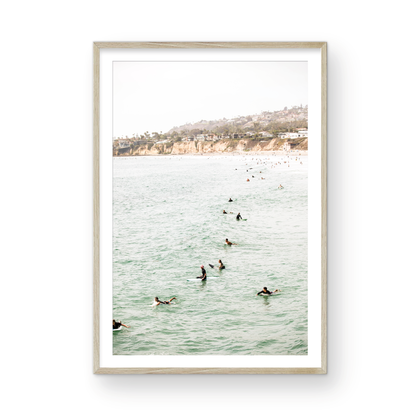 Vertical surf print showing several surfers paddling in the ocean at Pacific Beach, with a distant coastline. This image captures the surfing art of Southern California. Photograph in minimalist mock up.