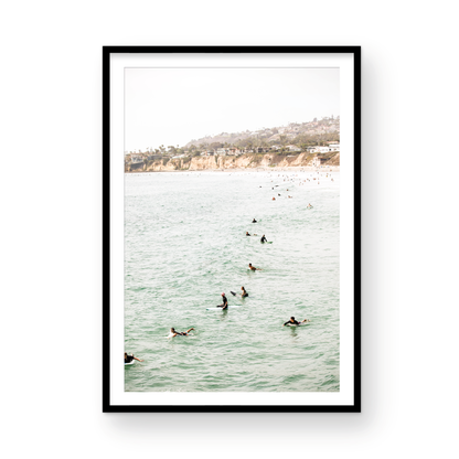 Vertical surf print showing several surfers paddling in the ocean at Pacific Beach, with a distant coastline. This image captures the surfing art of Southern California. Photograph in minimalist mock up.
