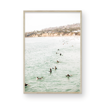 Vertical surf print showing several surfers paddling in the ocean at Pacific Beach, with a distant coastline. This image captures the surfing art of Southern California. Photograph in minimalist mock up.