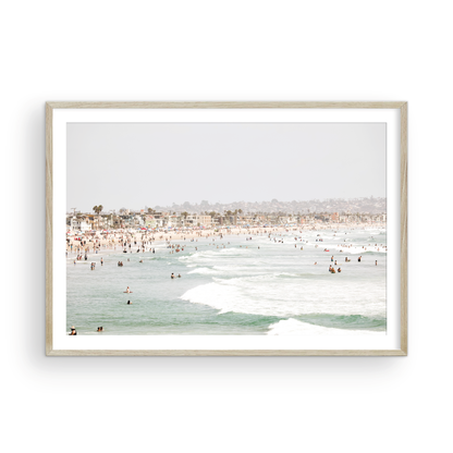 Landscape beach photography of a busy San Diego public beach with many people in the sand and ocean waves, a true summer vibes scene. Photograph in minimalist mock up.