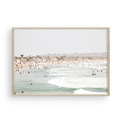 Landscape beach photography of a busy San Diego public beach with many people in the sand and ocean waves, a true summer vibes scene. Photograph in minimalist mock up.