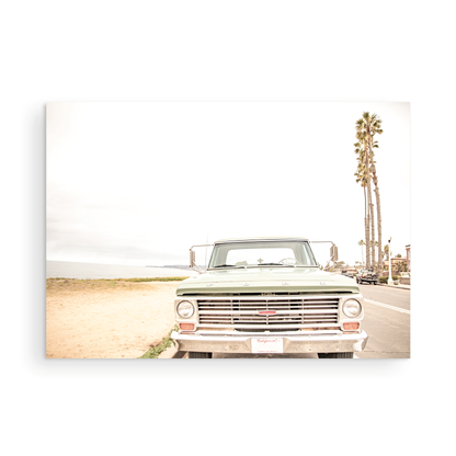 Nostalgic Southern California beach art featuring a classic light green Ford F-Series pickup truck parked by the San Diego coast. This horizontal surf print captures the vintage vehicle with a backdrop of iconic tall palm trees, a hazy beach, and the ocean, embodying surf vibes and perfect for coastal farmhouse decor. Photograph in minimalist unframed mock up.