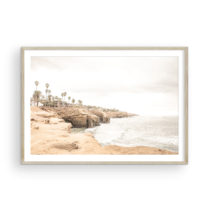 Fine art of Sunset Cliffs, San Diego California horizontal print of hazy high-angle landscape beach photography captures a light blue ocean meeting tall tan, brown cliffs rise as iconic coastal scenery. Photograph in minimalist mock up.