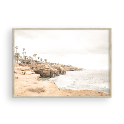 Fine art of Sunset Cliffs, San Diego California horizontal print of hazy high-angle landscape beach photography captures a light blue ocean meeting tall tan, brown cliffs rise as iconic coastal scenery. Photograph in minimalist mock up.