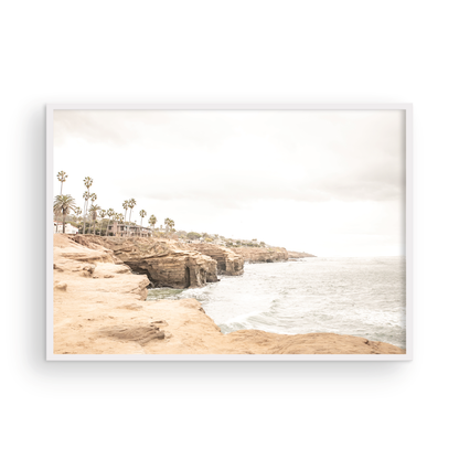 Fine art of Sunset Cliffs, San Diego California horizontal print of hazy high-angle landscape beach photography captures a light blue ocean meeting tall tan, brown cliffs rise as iconic coastal scenery. Photograph in minimalist mock up.