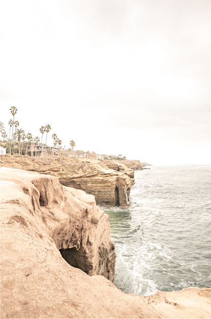 Fine art of Sunset Cliffs, San Diego California vertical print of hazy high-angle landscape beach photography captures a light blue ocean meeting tall tan, brown cliffs rise as iconic coastal scenery.