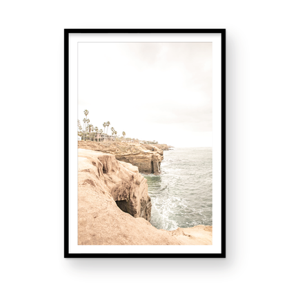 Fine art of Sunset Cliffs, San Diego California vertical print of hazy high-angle landscape beach photography captures a light blue ocean meeting tall tan, brown cliffs rise as iconic coastal scenery. Photograph in minimalist mock up.