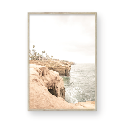 Fine art of Sunset Cliffs, San Diego California vertical print of hazy high-angle landscape beach photography captures a light blue ocean meeting tall tan, brown cliffs rise as iconic coastal scenery. Photograph in minimalist mock up.