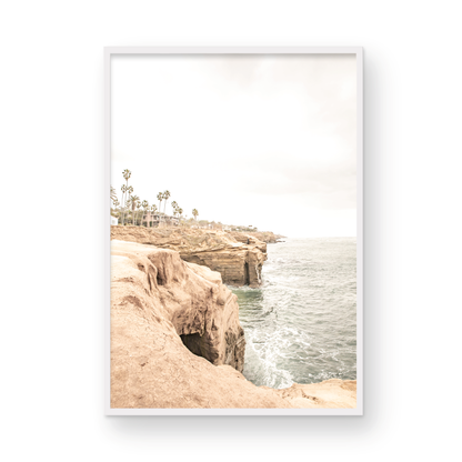 Fine art of Sunset Cliffs, San Diego California vertical print of hazy high-angle landscape beach photography captures a light blue ocean meeting tall tan, brown cliffs rise as iconic coastal scenery. Photograph in minimalist mock up.