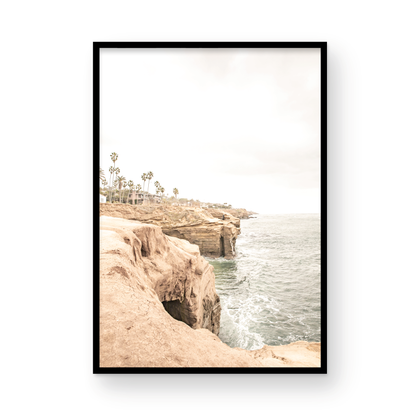 Fine art of Sunset Cliffs, San Diego California vertical print of hazy high-angle landscape beach photography captures a light blue ocean meeting tall tan, brown cliffs rise as iconic coastal scenery. Photograph in minimalist mock up.