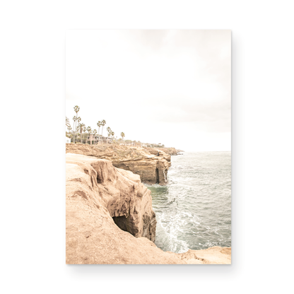 Fine art of Sunset Cliffs, San Diego California vertical print of hazy high-angle landscape beach photography captures a light blue ocean meeting tall tan, brown cliffs rise as iconic coastal scenery. Photograph in minimalist mock up.