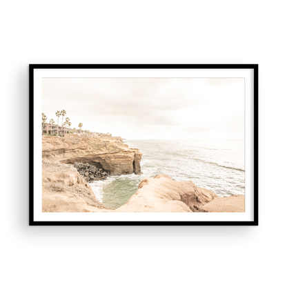 Fine art of Sunset Cliffs, San Diego California horizontal print of hazy high-angle landscape beach photography captures a light blue ocean meeting tall tan, rocky, brown cliffs rise as iconic coastal scenery. Photograph in minimalist mock up.